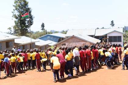 Learners gathered outdoors near the school buildings.