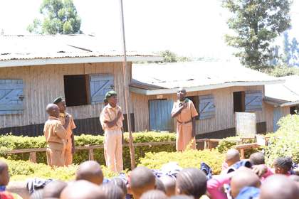 Learners standing in formation near the flagpole during assembly.
