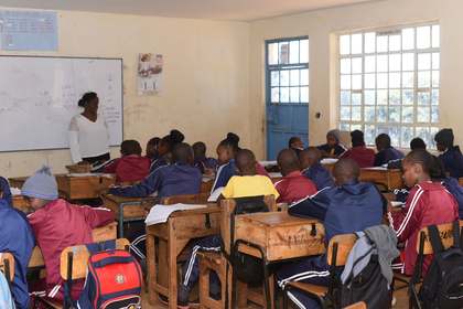 A teacher at the whiteboard with learners at their desks.