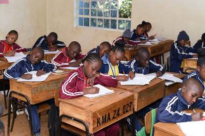 Learners at their desks with exercise books open.