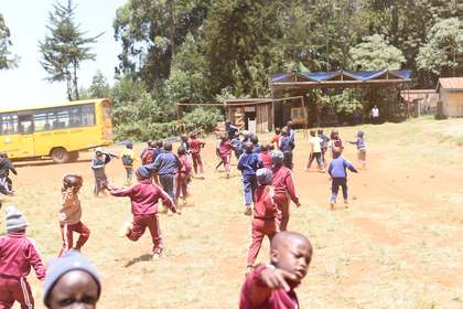 Learners playing together, with school buildings in the background.
