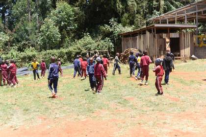 A wide view of learners playing on the field.