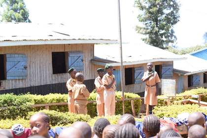 A Scout leading part of the flag ceremony beside the school's activities signboard.