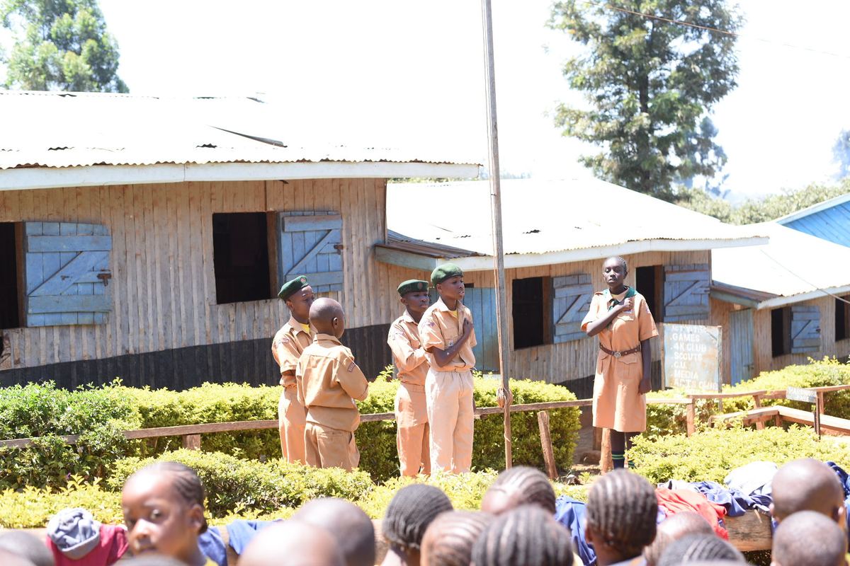 A Scout leading part of the flag ceremony beside the school's activities signboard.